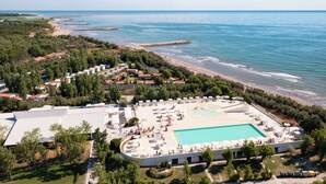 Vista aérea de un resort con piscina, acceso a la playa y vegetación circundante.