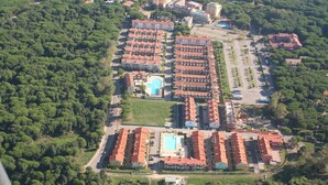 Vue aérienne d’un complexe hôtelier comprenant plusieurs bâtiments, une piscine et une végétation luxuriante.