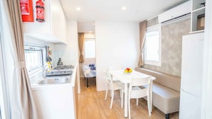 Een compact keukenhoekje met een gasfornuis, spoelbak en een kleine eettafel met stoelen.