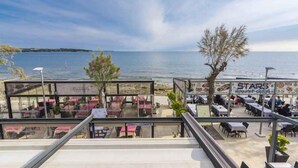 Un restaurante frente al mar con terraza y vistas al océano, con un cartel de menú y un letrero de pizza.