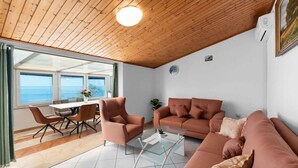 Una sala de estar acogedora con techo de madera, un sofá, una mesa de centro y un comedor con mesa y sillas.