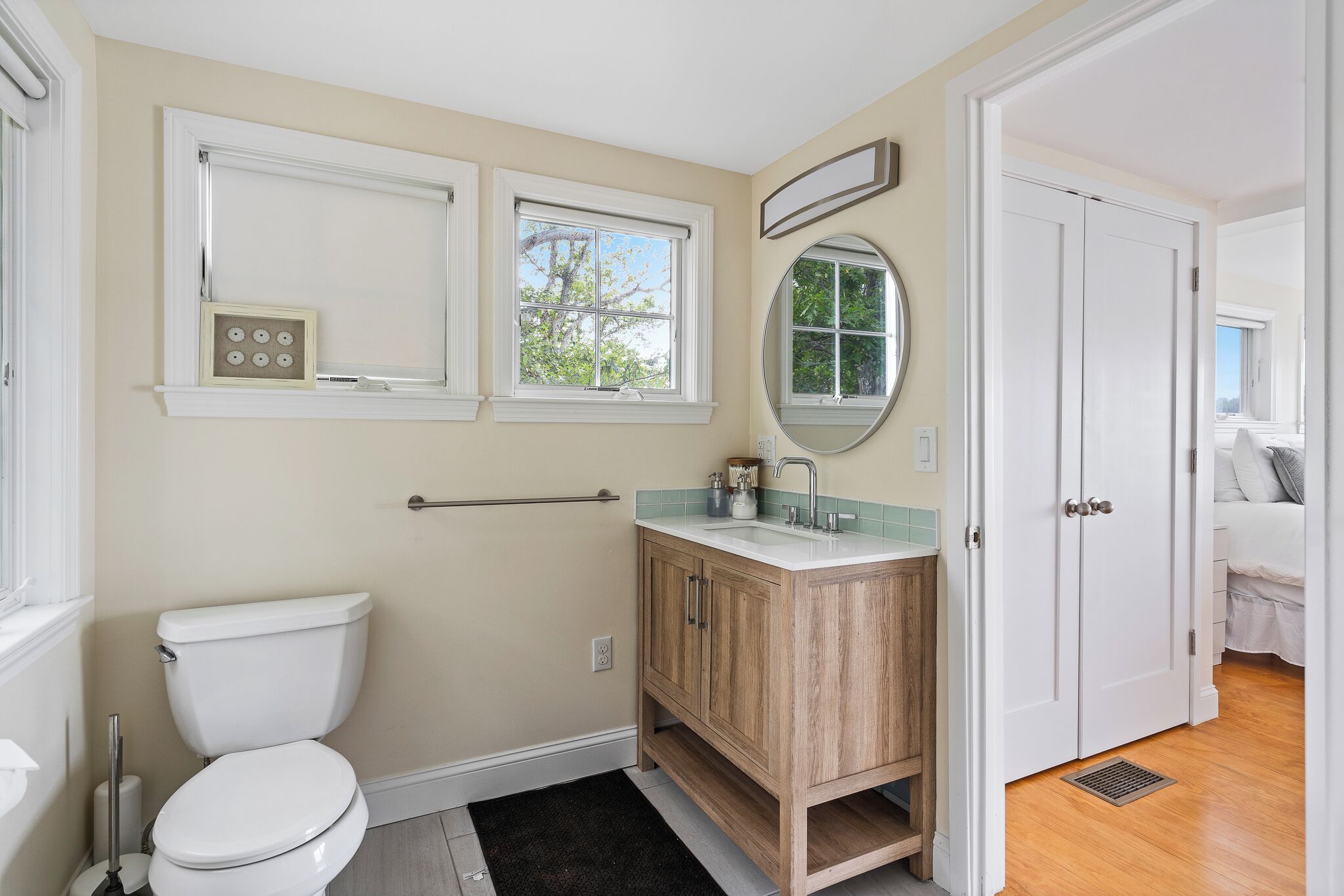 A bathroom with a toilet, vanity, and a window.