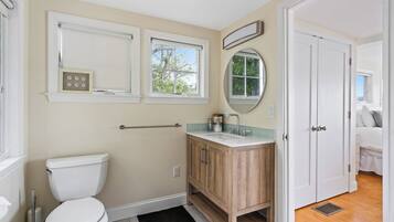 A bathroom with a toilet, vanity, and a window.