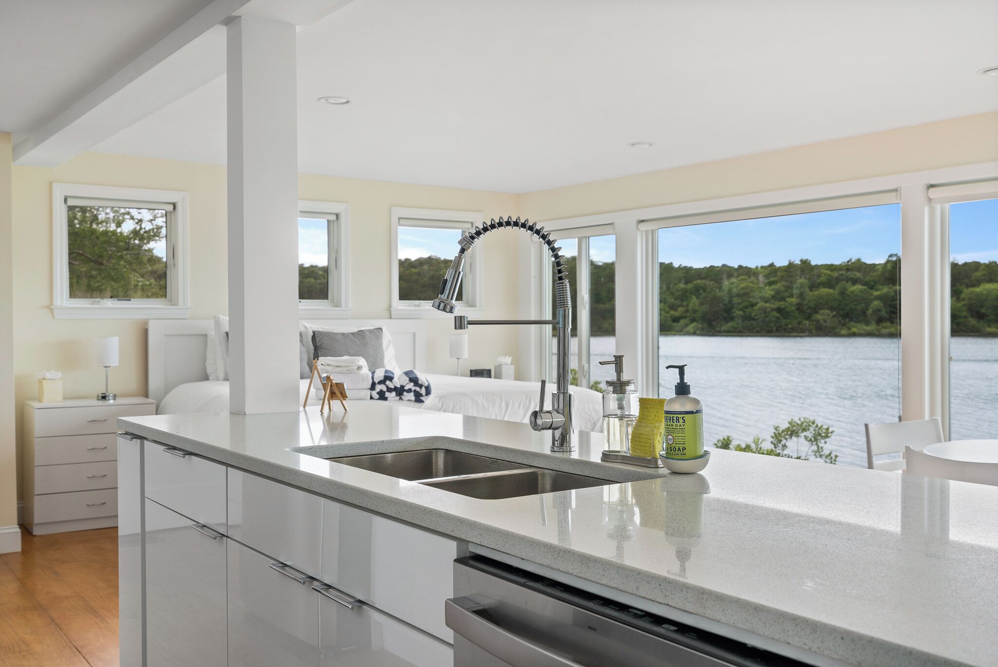 A modern kitchen with a large window, a built-in sink, and a view of a lake.