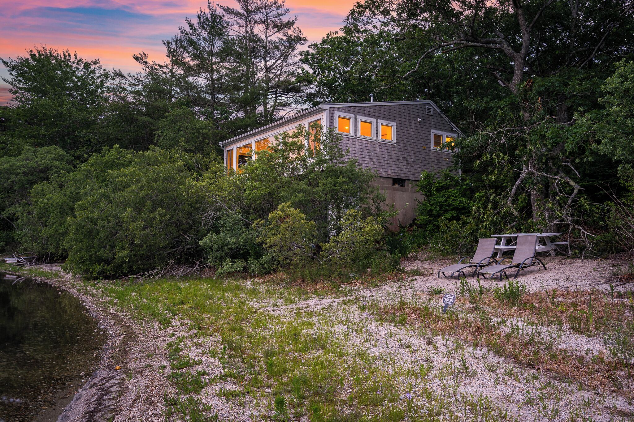 A house surrounded by dense trees and a body of water.