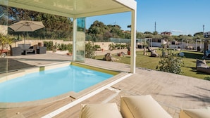 A modern outdoor pool area with a glass enclosure, outdoor furniture, and a view of the surrounding landscape. - Ammentos by Interhome (Marina di Sorso)