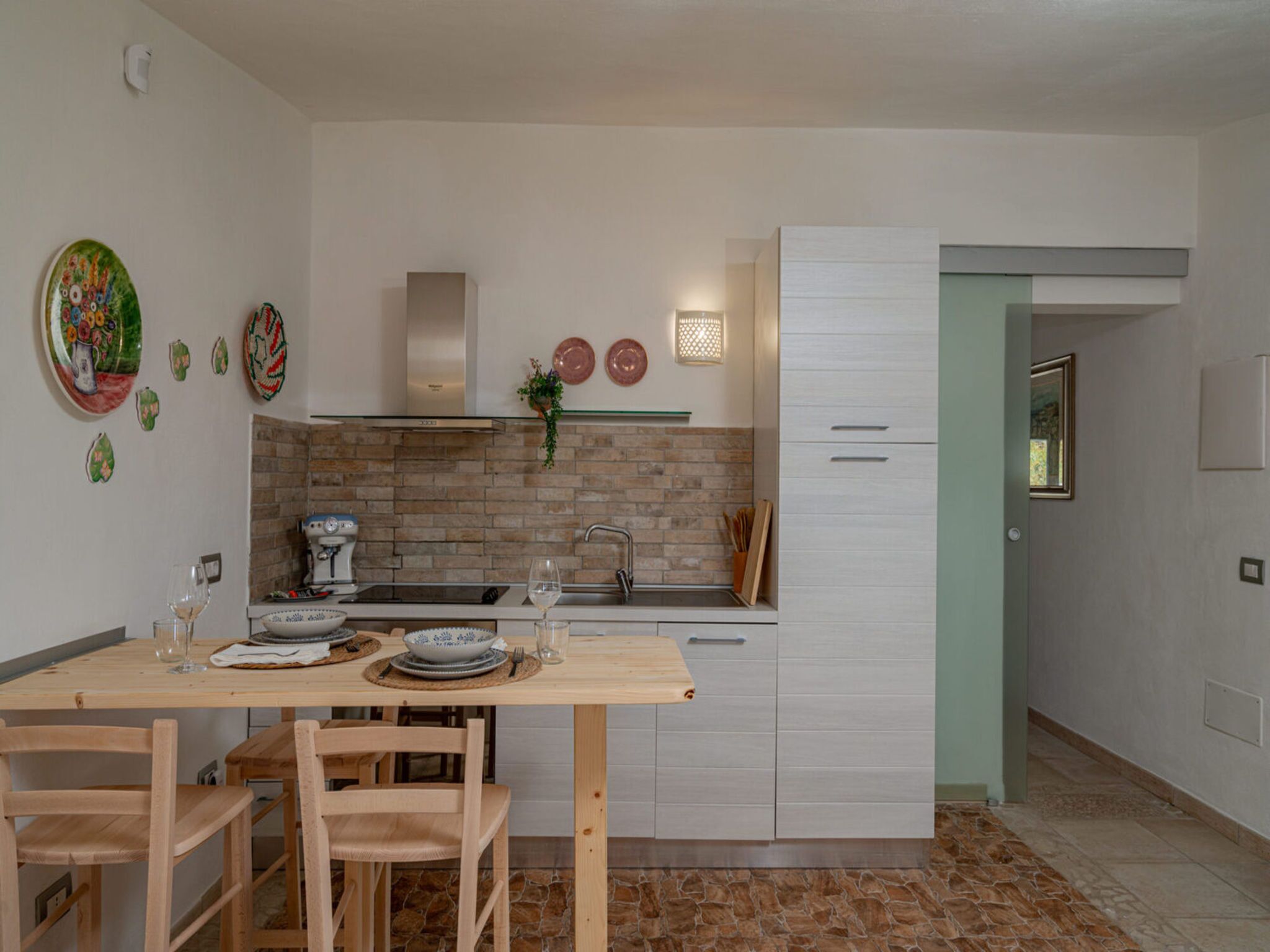 A modern kitchen with a wooden table, chairs, a built-in oven, and a white cabinet.