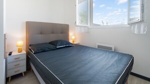 Une chambre à coucher avec un lit, des lampes de chevet, une table de chevet et une fenêtre avec des rideaux.