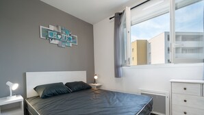 Une chambre à coucher comprenant un lit, des tables de chevet, une commode, une fenêtre avec des rideaux et un élément de décoration murale.