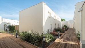 Stylish building with multiple levels, featuring clean lines and a neutral palette, surrounded by lush greenery and a wooden walkway.