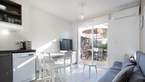 A modern kitchen with white cabinetry, a built-in dishwasher, and a dining area with white chairs. - Bright villa 4 ppl, garden, close to the sea (Sérignan)
