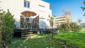 A patio with outdoor furniture, a covered seating area, and a view of a modern building. - Bright villa 4 ppl, garden, close to the sea (Sérignan)
