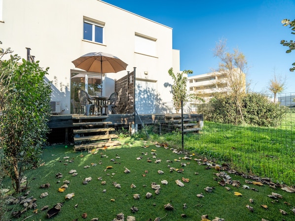 Une terrasse avec des meubles d’extérieur, un espace salon couvert et une vue sur un bâtiment moderne.