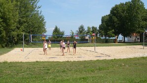 Ein Volleyballfeld mit Netz, umgeben von Sand und Gras.
