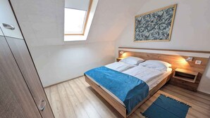 Ein Schlafzimmer mit Bett, Nachttisch, Nachttischlampe, Fenster und einem Bild an der Wand.