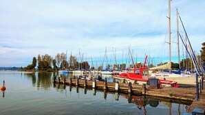 A marina with multiple sailboats docked along the shore, calm water, and a clear sky. - Holiday apartment directly on the water with free beach (Zamárdi)