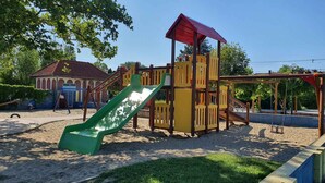 A playground with a slide, swings, and a climbing structure. - Holiday apartment directly on the water with free beach (Zamárdi)