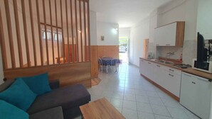 A modern living room with a sofa, a coffee table, and a dining area with a table and chairs. - Holiday apartment directly on the water with free beach (Zamárdi)
