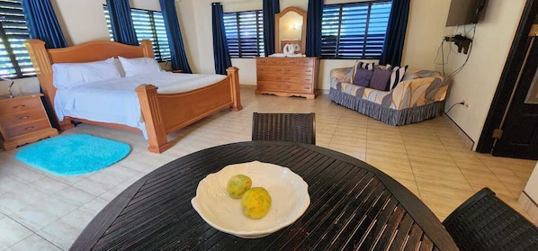Un dormitorio con cama, cómoda y sofá. Hay una mesa con un plato de comida.