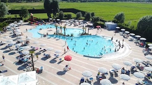 A large outdoor swimming pool with multiple lanes, surrounded by sun loungers and umbrellas. - Mobile home with air conditioning, terrace and pool (Caorle)