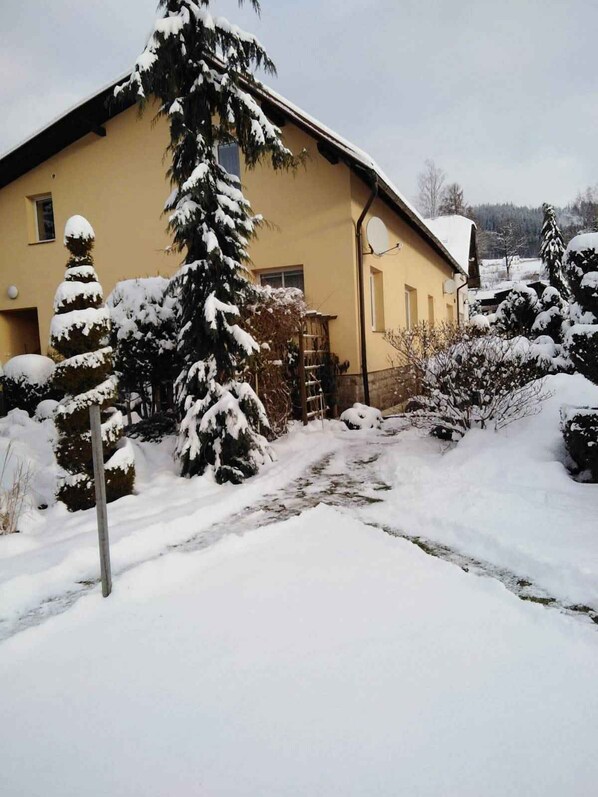A yellow building with a snow-covered roof and surrounding trees.