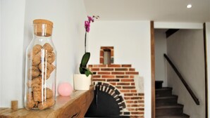 Une étagère en bois sur laquelle se trouve un bocal en verre rempli de bouchons, une bougie rose et une plante en pot.