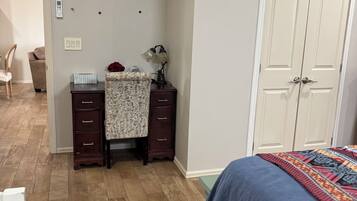 Une chambre à coucher comprenant un lit, une commode, un bureau avec une lampe, une chaise et une armoire.