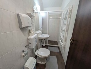 Une petite salle de bain comprenant des toilettes, un lavabo et un distributeur de serviettes.