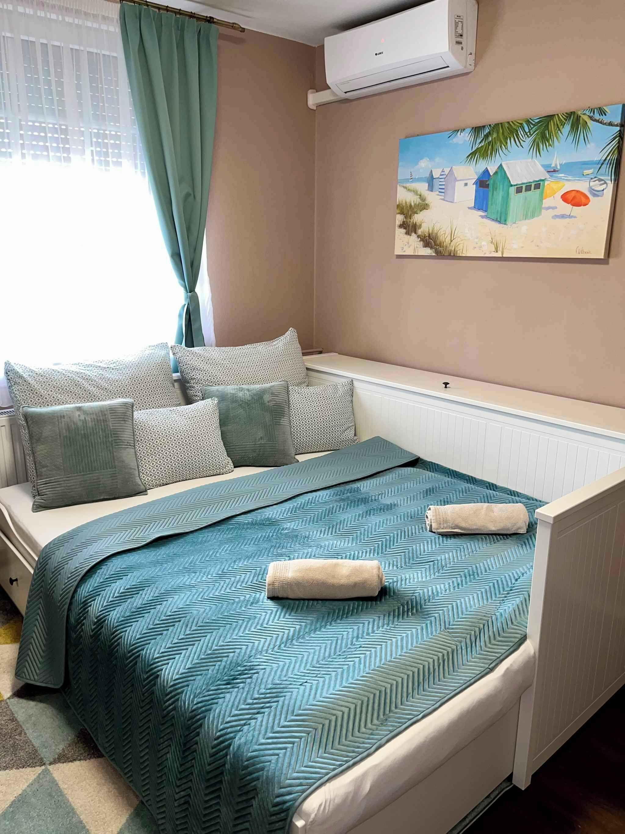 Ein Schlafzimmer mit einem Bett, Kissen, einem Gemälde und einer Klimaanlage.