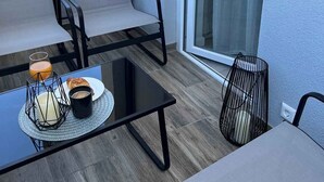 Ein Balkon mit Tisch, zwei Stühlen und einer Glastür.