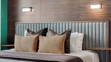 A modern hotel room with a large bed, a padded headboard, and two bedside tables.