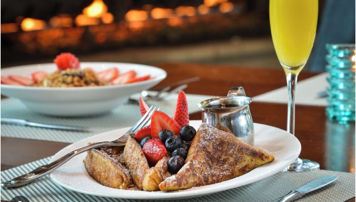 A breakfast setting with toast, strawberries, blueberries, and a glass of orange juice.