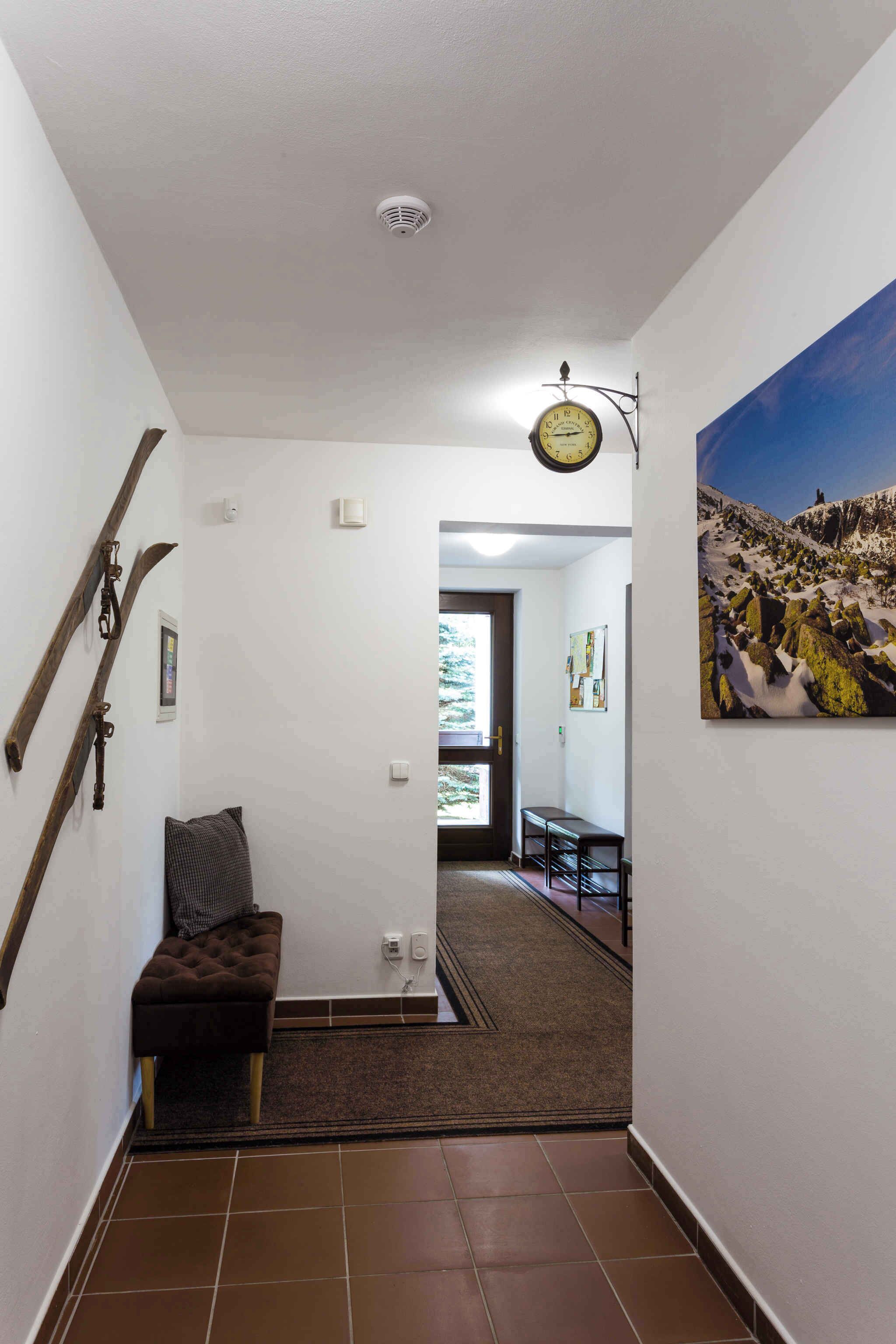 A hallway with a brown bench, a clock, and a painting of a snowy landscape.