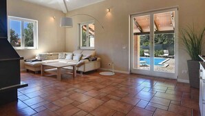A spacious living room with a sofa, coffee table, and a large window overlooking a pool.