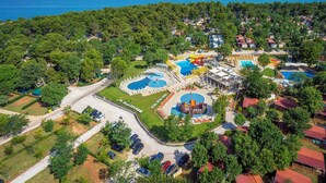 Luchtbeeld van een resort met meerdere zwembaden, een waterpark en een strand op de achtergrond.