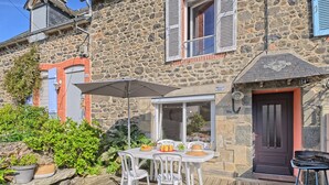 A stone building with a wooden deck, outdoor seating, and a barbecue area.