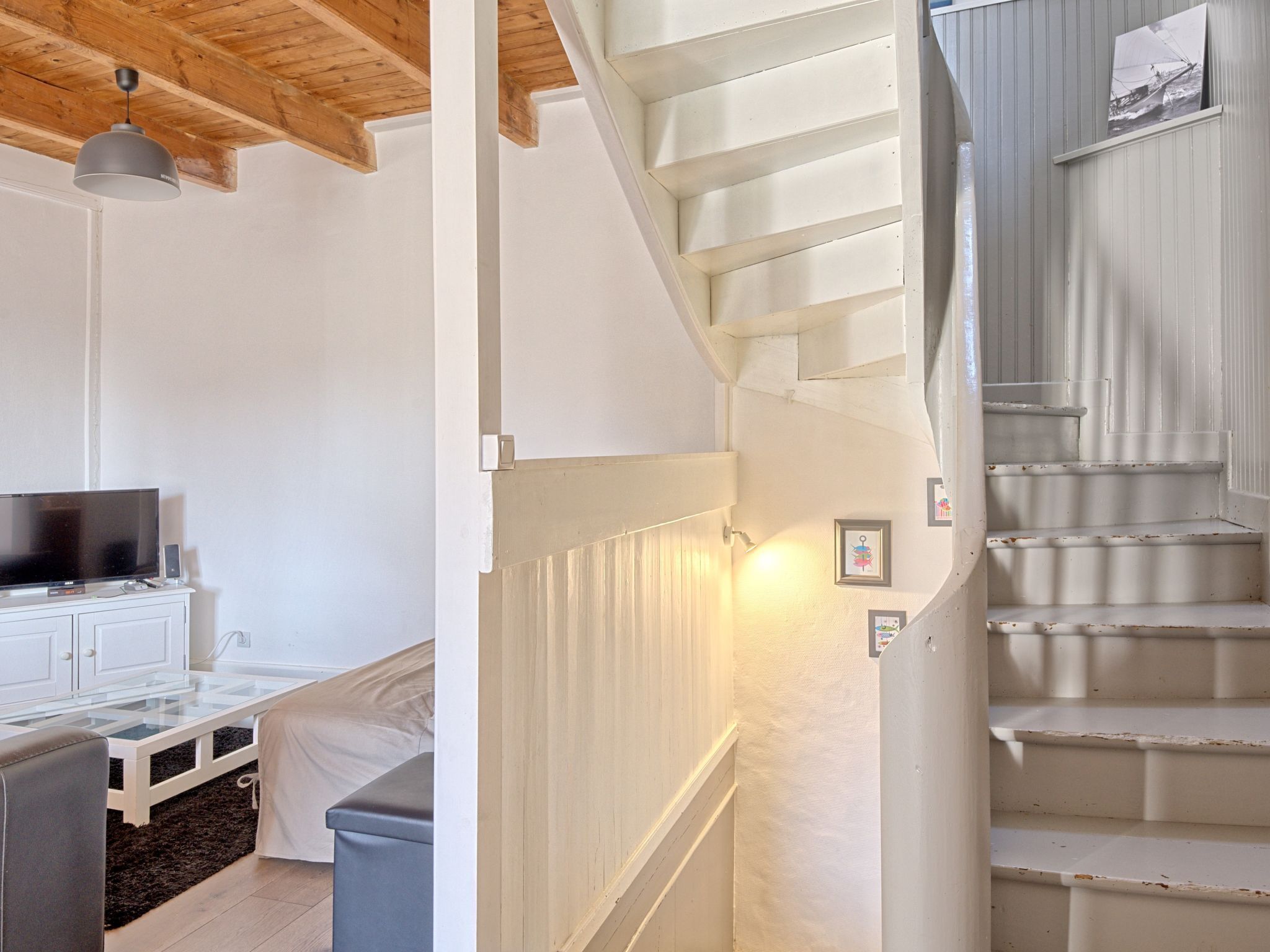 Een modern interieur met een trap, een flatscreen-tv en een witte kast.