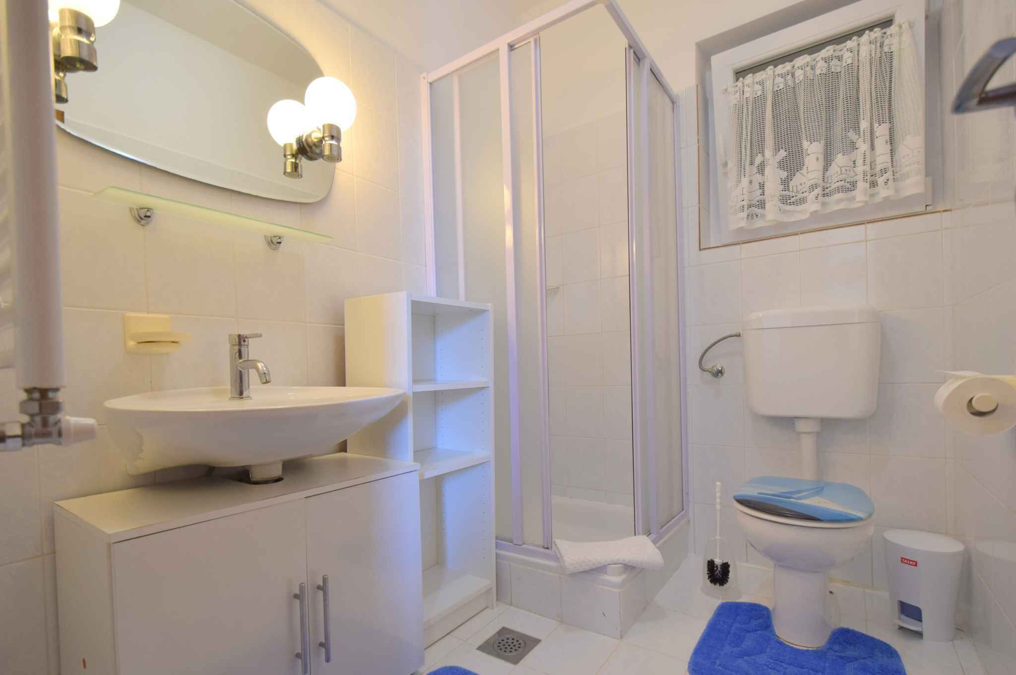 A bathroom with a white sink, mirror, toilet, and shower.