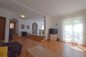 A spacious living area with a sofa, TV, and a staircase leading to a kitchen. - Holiday flat with sea view (Omišalj)