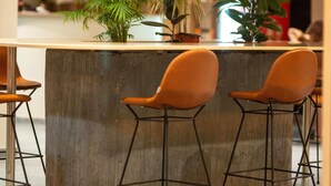 A bar area with a concrete counter, two orange bar stools, and potted plants. - iLLYRIA HOTEL (Ulcinj)