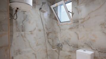 Een moderne badkamer met toilet, douche en dakraam.