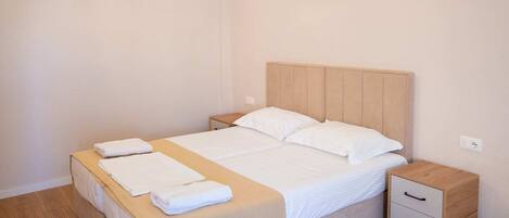 Un dormitorio ordenado con cama, mesitas de noche y una lámpara colgante.