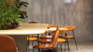 A modern dining area with a long table, several chairs, and a potted plant. - iLLYRIA HOTEL (Ulcinj)