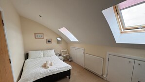 Une chambre à coucher comprenant un lit, un radiateur, une armoire, un puits de lumière et une porte.