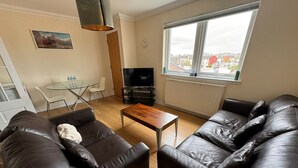 A modern living room with leather sofas, a wooden coffee table, a TV, and a dining area with a glass table and chairs. - Convenient Edinburgh City Centre 2 Rooms + Parking (Edinburgh)