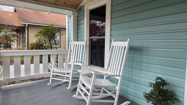 A porch with two rocking chairs and a small tree.