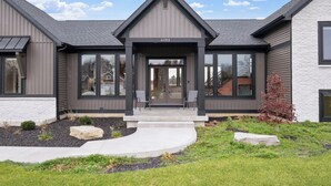 A modern two-story house with a grey roof, large windows, and a number 6193 displayed above the entrance. - 7bd 8bath Hot tub, Pool, Game Room, Sauna, Professional Pickleball Court (Fennville)