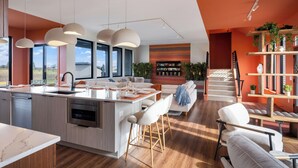 A modern kitchen with a central island, bar stools, and pendant lighting. - 7bd 8bath Hot tub, Pool, Game Room, Sauna, Professional Pickleball Court (Fennville)