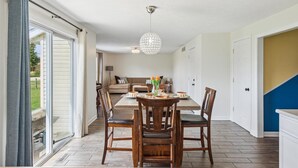 Un espace repas comprenant une table, des chaises et un lustre.