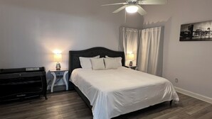 A neatly arranged bedroom with a bed, two bedside tables with lamps, a ceiling fan, and a painting on the wall. - Near universal studios Charming 4bed house with WiFi, AC in enjoyable Orlando (Orlando)